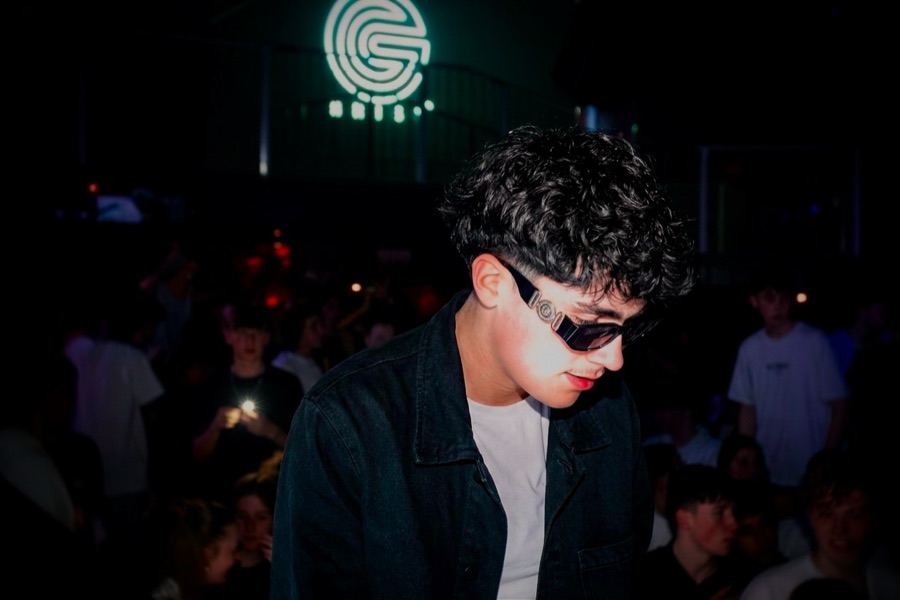 Thamis en boîte de nuit, lunettes noires, la foule derrière lui